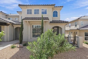 A two-story house with a tiled roof, a central entrance with a glass door, and a small garden area with gravel and plants. - Mirador Sol - Pool Access (Washington)