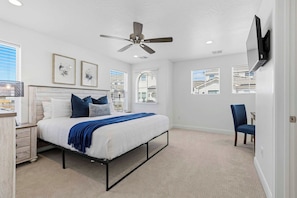 A bedroom with a bed, a desk, a chair, a ceiling fan, and a TV mounted on the wall. - Mirador Sol - Pool Access (Washington)