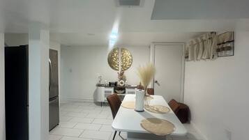 A modern dining area with a white table, brown chairs, and a decorative wall piece.