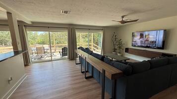 A modern living room with a sofa, TV, and a balcony with outdoor furniture.