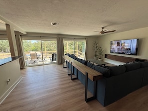 A modern living room with a sofa, TV, and a balcony with outdoor furniture.