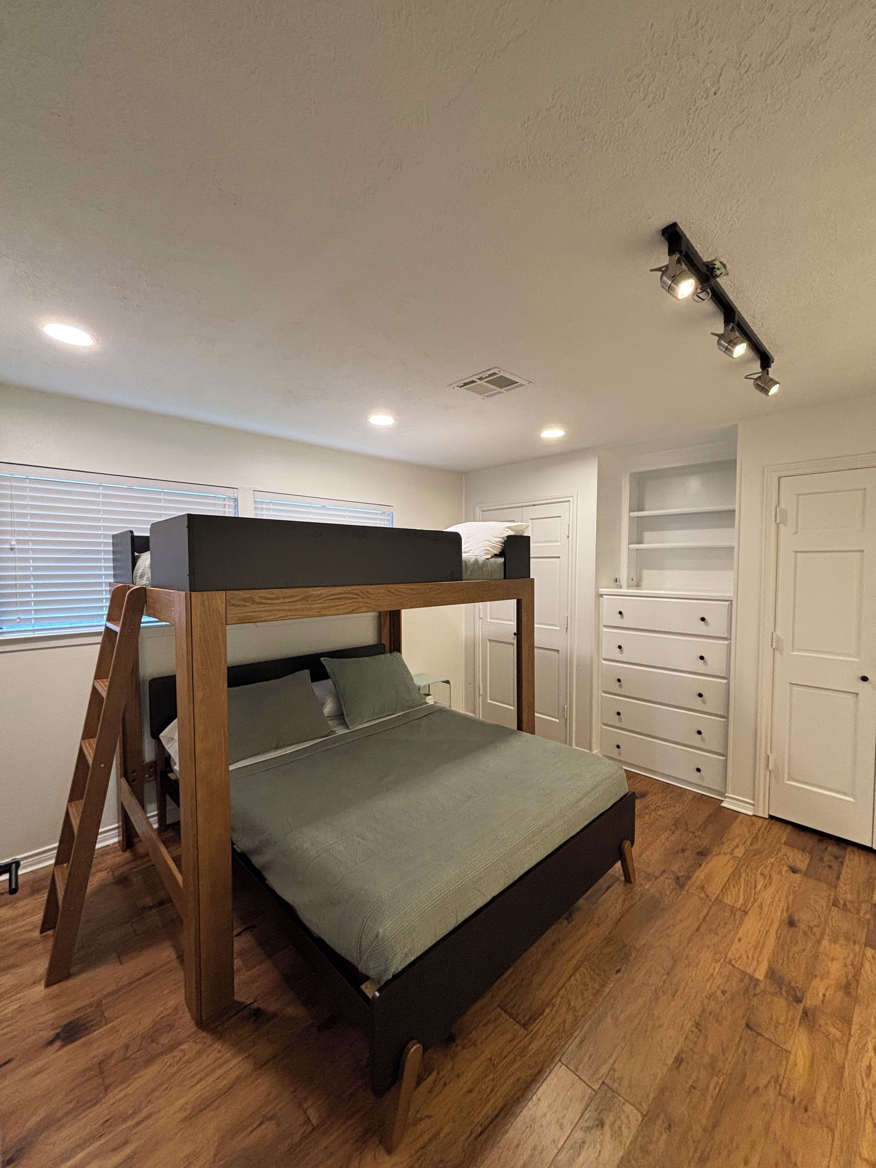 A bunk bed with a ladder, a white wardrobe, and a door with a closet.