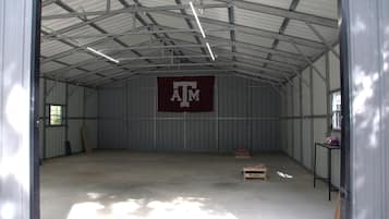 Un grand entrepôt vide, avec un plafond haut et des murs en métal. Une grande bannière de couleur bordeaux, sur laquelle on peut lire les lettres « ATM », est visible sur le mur.