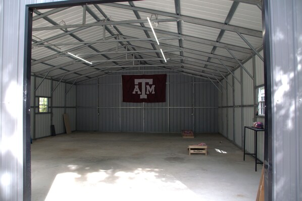 A large, empty warehouse with a high ceiling and metal walls. A large maroon banner with the letters 'ATM' is visible on the wall.