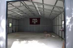 A large, empty warehouse with a high ceiling and metal walls. A large maroon banner with the letters 'ATM' is visible on the wall.