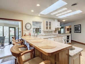 A kitchen with a long island, wooden chairs, and a clock on the wall. - Tremendous house with AC in sunny Vero Beach (Vero Beach)