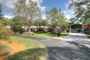 A residential property with a paved driveway, a covered garage, and a variety of trees and shrubs. - Tremendous house with AC in sunny Vero Beach (Vero Beach)
