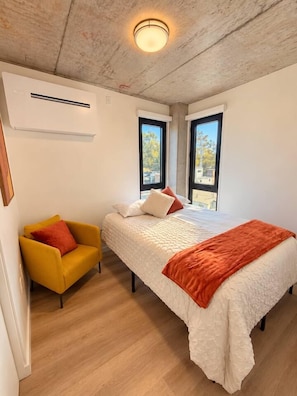 A bedroom with a bed, a chair, and an air conditioning unit. - The Ember Retreat !! (San Diego)