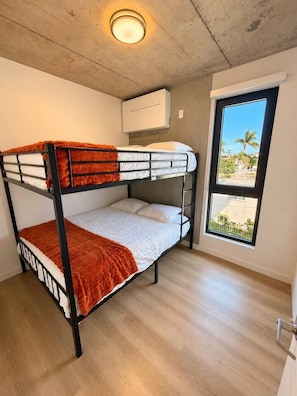 A bunk bed with a red blanket, a window with a view of palm trees, and a ceiling light fixture. - The Ember Retreat !! (San Diego)