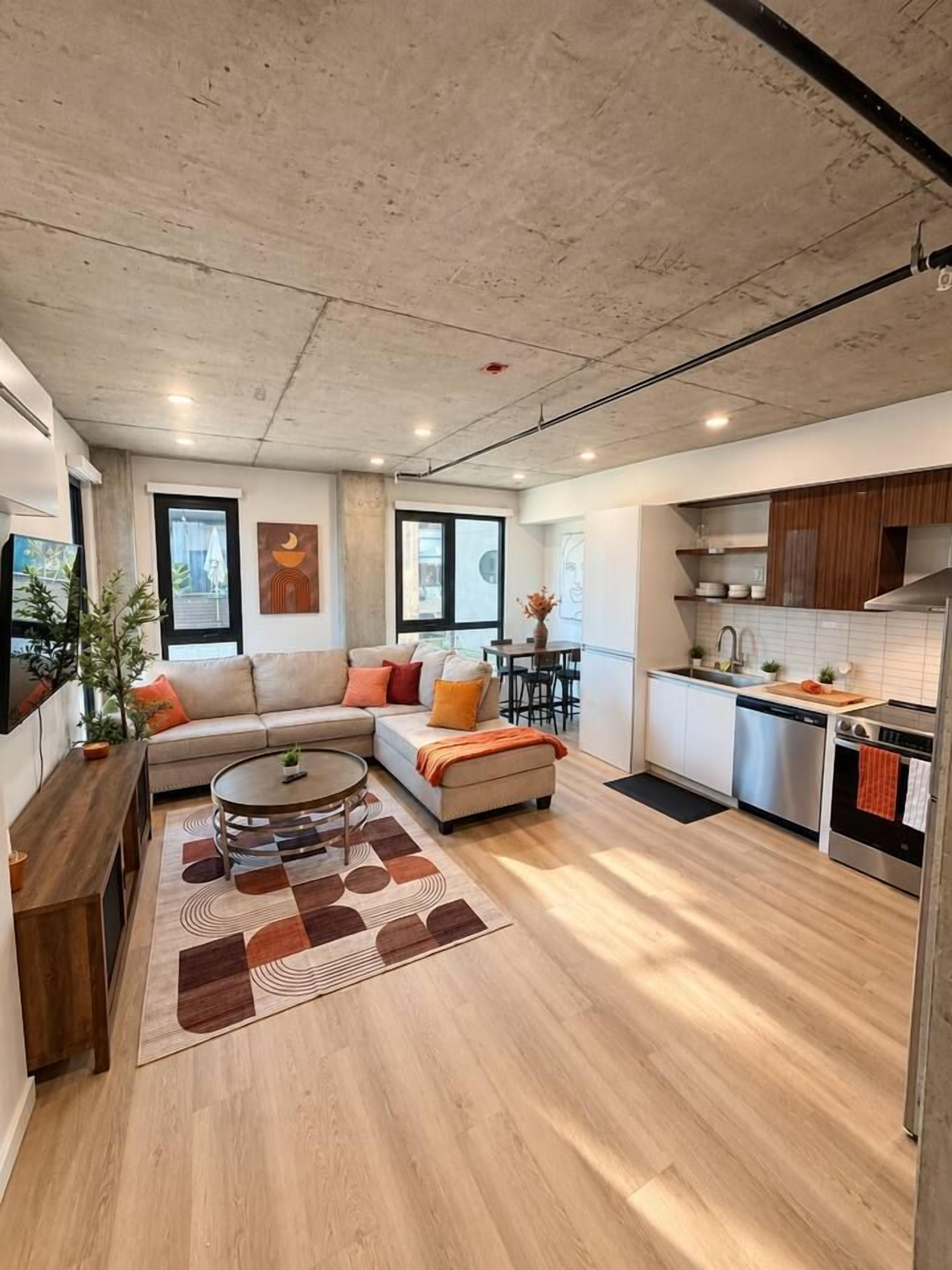Un espacio habitable moderno con un sofá, una mesa de centro y una zona de cocina con electrodomésticos.