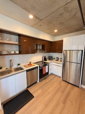 A modern kitchen with stainless steel appliances, wooden cabinets, and a black rug. - The Ember Retreat !! (San Diego)