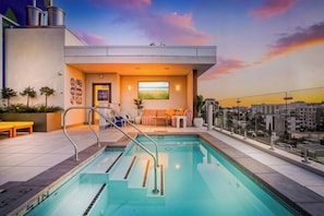A rooftop swimming pool with a lounge area, a view of the city, and a sunset. - The Ember Retreat !! (San Diego)