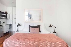 Une chambre à coucher avec un lit, des tables de chevet, une lampe et un tableau encadré au mur.