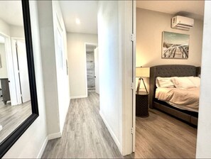 Un dormitorio con cama, mesita de noche, lámpara y un cuadro en la pared.