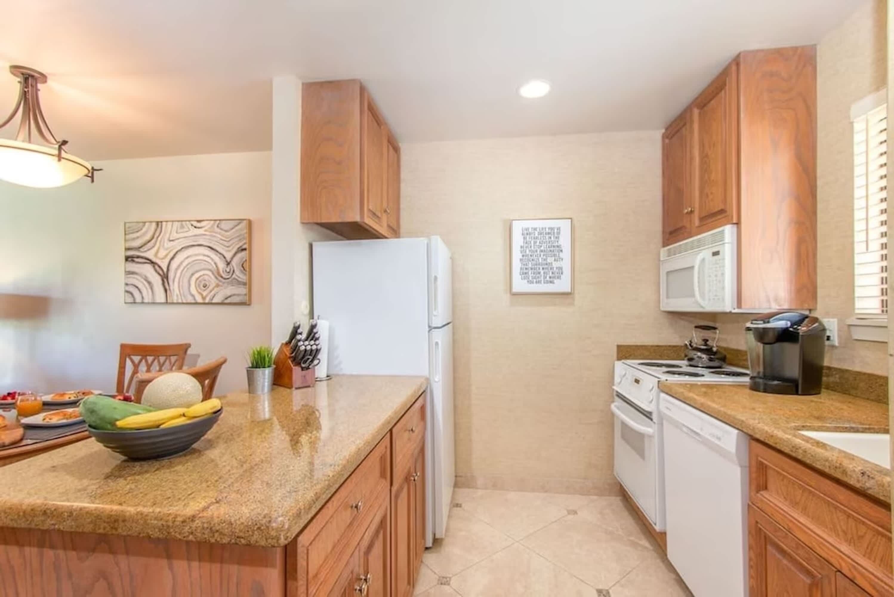A compact kitchen with wooden cabinets, a white refrigerator, a microwave, and a stove.