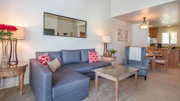 Ein Wohnzimmer mit Ecksofa, Couchtisch und einem Essbereich mit Tisch und Stühlen.