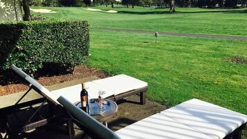 Campo de golf con un área de descanso que incluye una mesa, sillas y una botella de vino.
