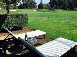 Campo de golf con un área de descanso que incluye una mesa, sillas y una botella de vino.