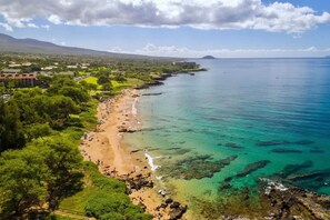 A coastal landscape with a beach, clear waters, and a mountainous backdrop. - 2 Bedrooms Condo, Steps From the Beach (Kihei)