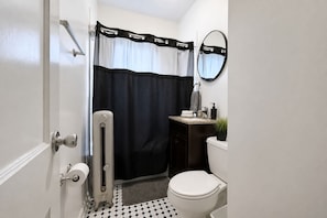 A bathroom with a toilet, a sink, a mirror, a towel rack, and a shower curtain.