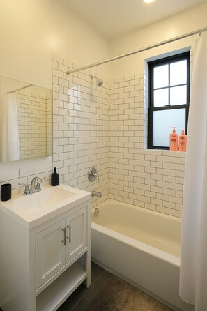 A bathroom with a white sink, mirror, and bathtub. - Fully Set Up 3BR w/ Big Kitchen (Chicago)
