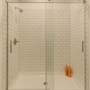 A walk-in shower with white subway tiles, a glass door, and a showerhead. - Fully Set Up 3BR w/ Big Kitchen (Chicago)