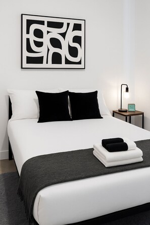 A modern bedroom with a bed, pillows, a bedside table with a lamp, and a wall art piece. - Stylish 4BR South Loop Home (Chicago)