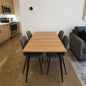 Une cuisine moderne dotée d’appareils électroménagers intégrés et d’un coin repas avec une table et des chaises en bois.