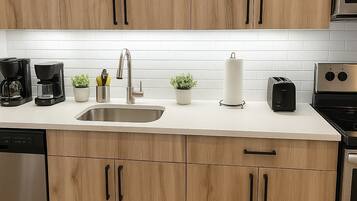 Une cuisine moderne avec des meubles en bois, des appareils en acier inoxydable et un plan de travail blanc.