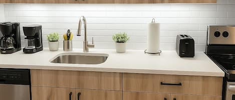 Una cocina moderna con armarios de madera, electrodomésticos de acero inoxidable y una encimera blanca.