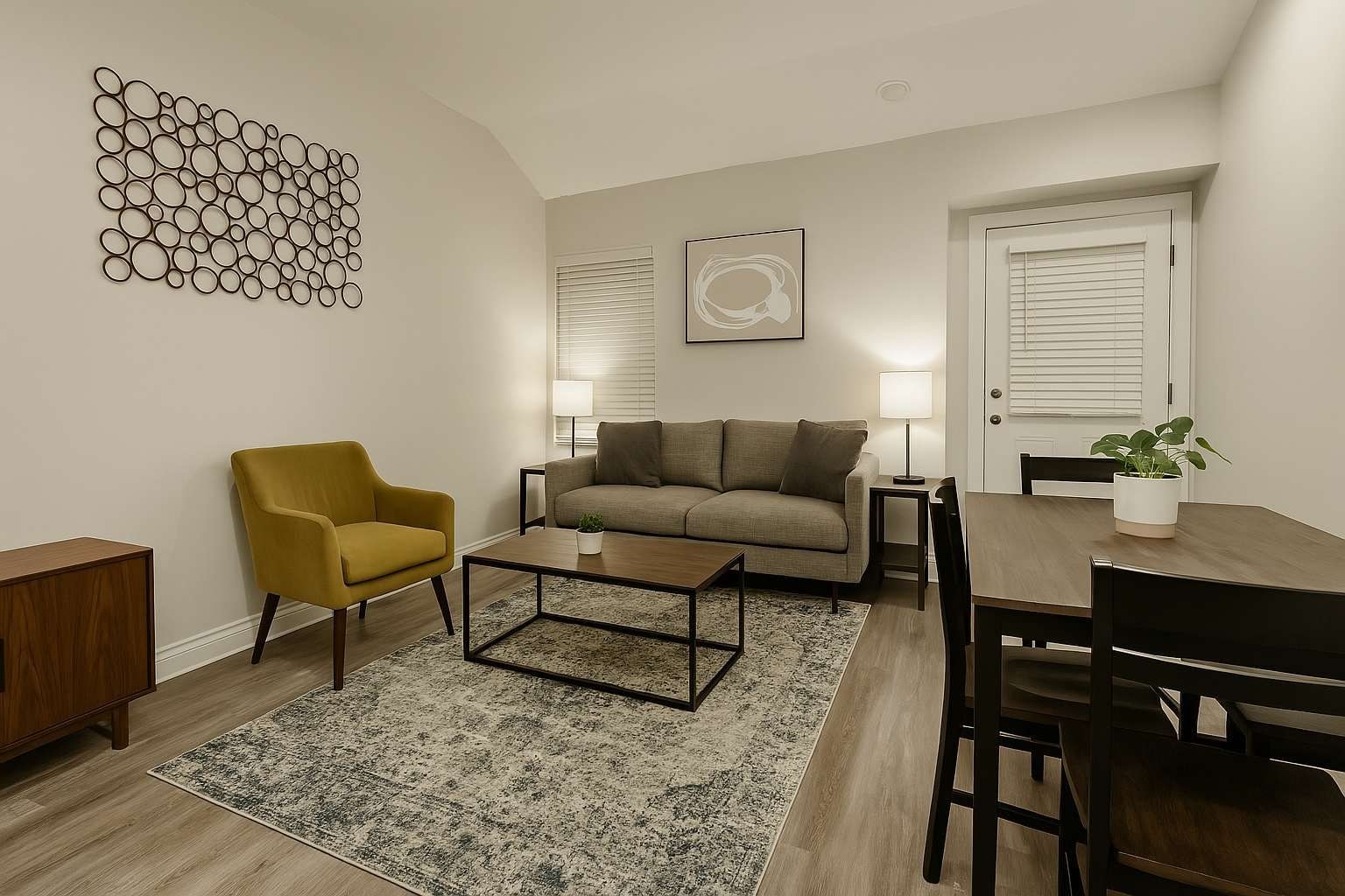 A living room with a sofa, armchair, coffee table, and dining table.