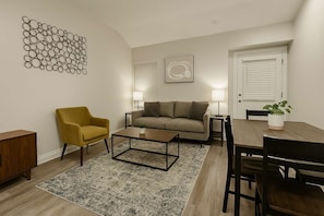A living room with a sofa, armchair, coffee table, and dining table. - 3BR Apt - Prime & Spacious (Chicago)