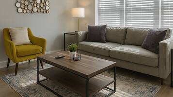 A living room with a sofa, armchair, coffee table, lamp, and wall decor.