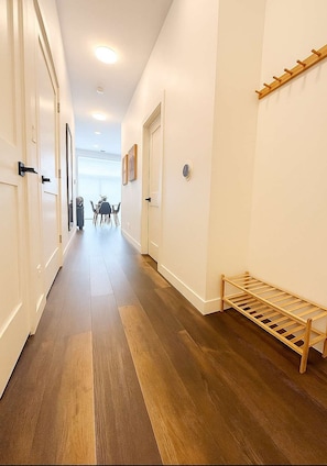 A hallway with wooden flooring, white walls, and a wooden bench. - Stylish 4BR Stay-Prime Location (Chicago)