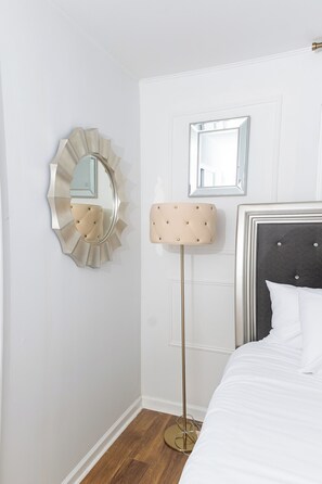 A bedroom with a bed, a floor lamp, and two wall mirrors.
