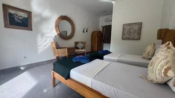 Un dormitorio con dos camas, cabecero de madera, tapiz tejido y una obra enmarcada en la pared.