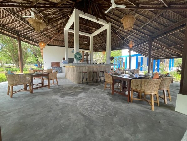 An outdoor covered area with a bar, seating arrangements, and a decorative ceiling.