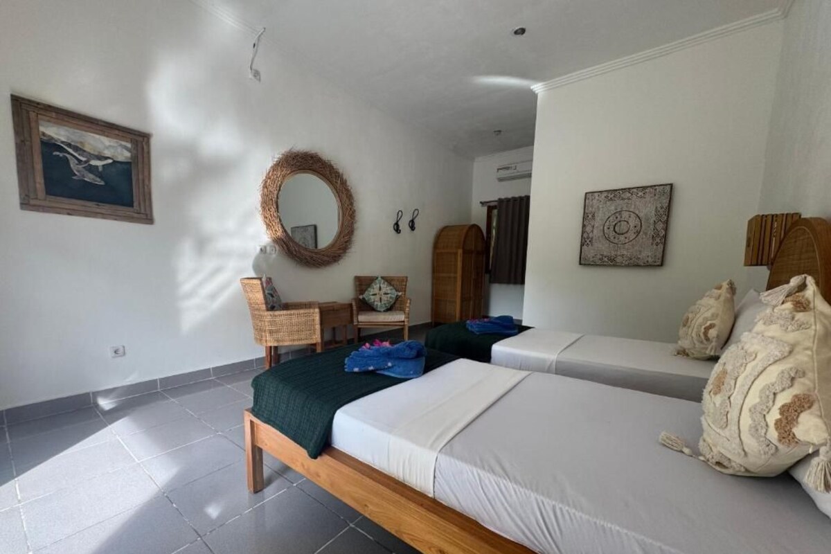 Quarto com duas camas, uma cabeceira de madeira, um painel de parede tecido e uma obra de arte emoldurada.