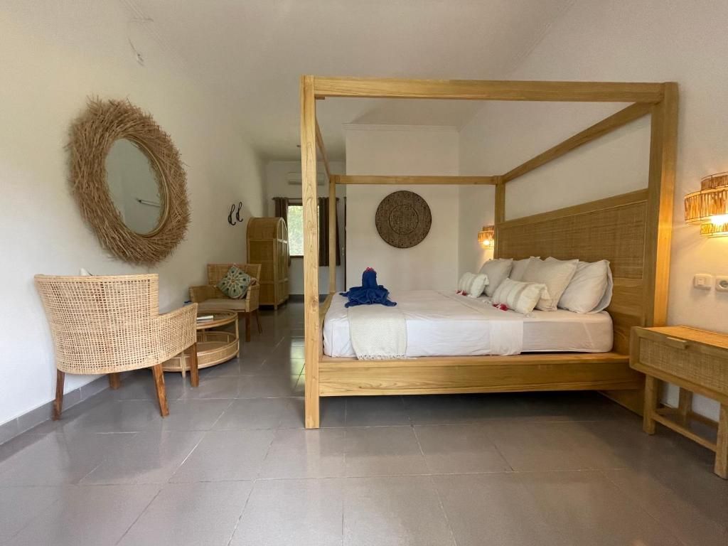 A room with a four-poster bed, a wicker chair, a round mirror, and a wall-mounted light fixture.