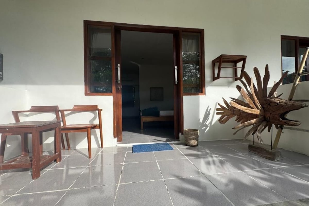 A room with a wooden chair, a small table, a large decorative piece, and a sliding door leading to another room.