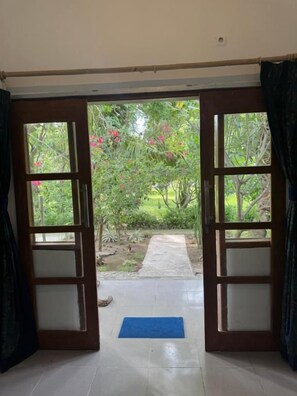 Quarto com porta aberta dando para um jardim.