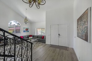 A spacious living room with a grey sofa, a coffee table, and a staircase with a black railing. - MV Pylos - Central - Nearby Restaurants/Freeway (Mission Viejo)