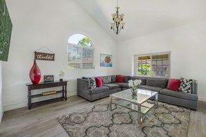 A spacious living room with a sectional sofa, a glass coffee table, and a decorative rug. - MV Pylos - Central - Nearby Restaurants/Freeway (Mission Viejo)