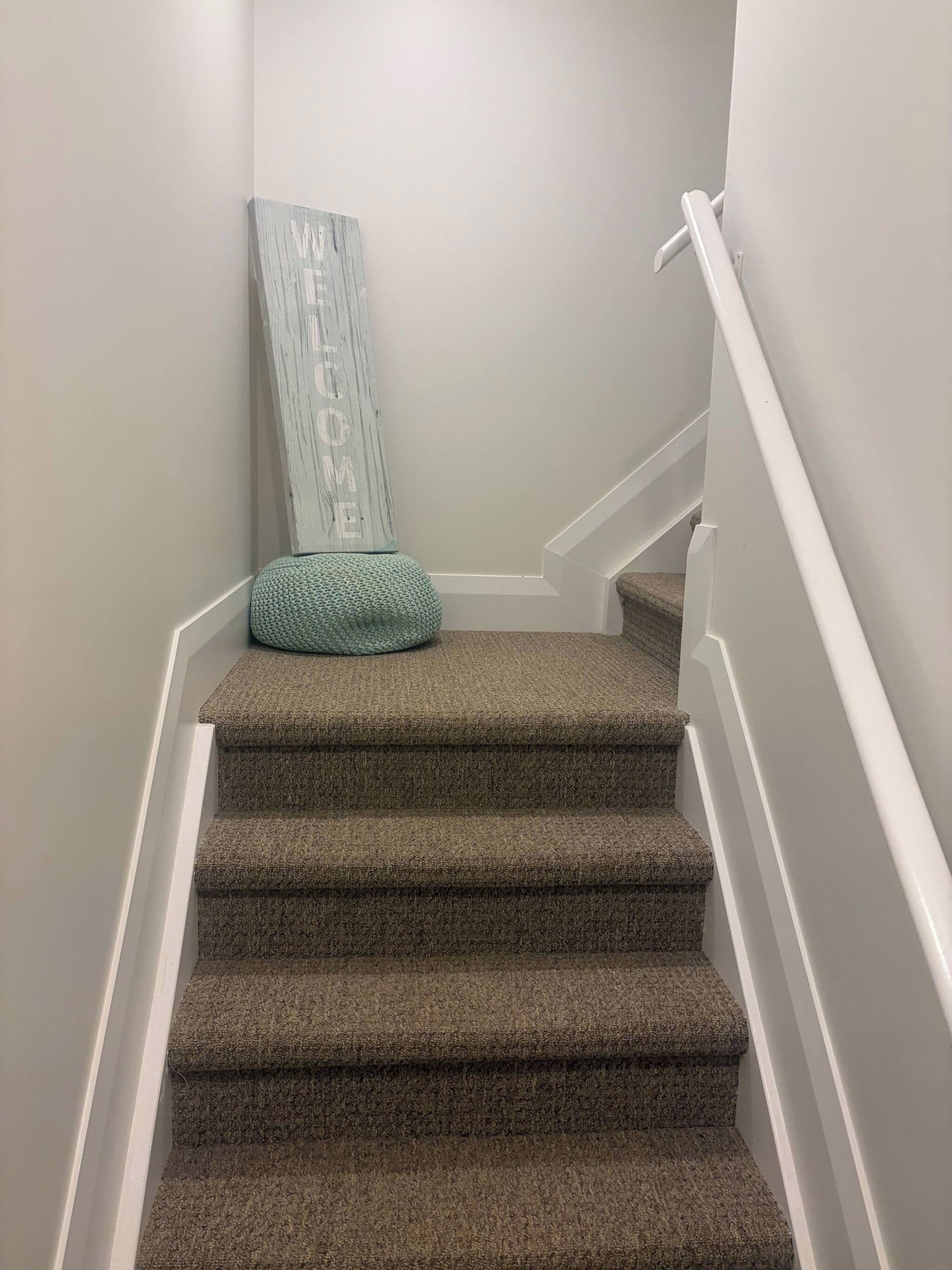 Una escalera alfombrada con felpudo y un adorno en la parte superior.