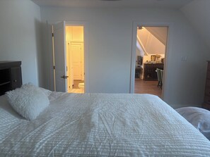A bedroom with a bed, a white fluffy pillow, and a door leading to a bathroom.