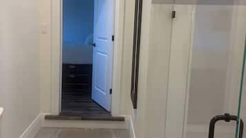 A modern bathroom with a toilet, a shower with a glass door, and a visible staircase leading to another room.