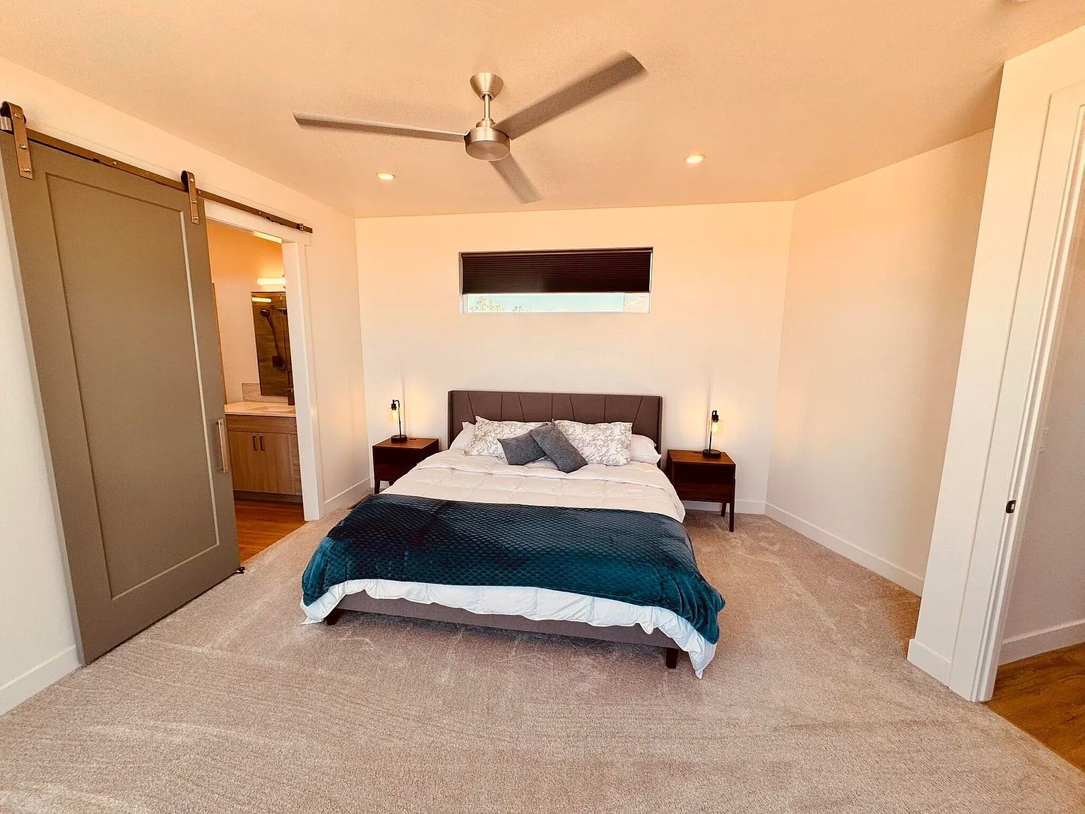 A bedroom with a bed, two bedside tables, a ceiling fan, a sliding door, and a window with blinds.