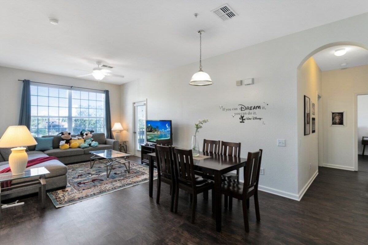 A modern living room with a sofa, TV, and dining area.