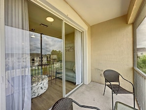 A balcony with a sliding glass door, a chair, and a patterned ottoman. - Windsor Palms 3 Bed Condo In Gated Resort 3 Bedroom Condo (Kissimmee)