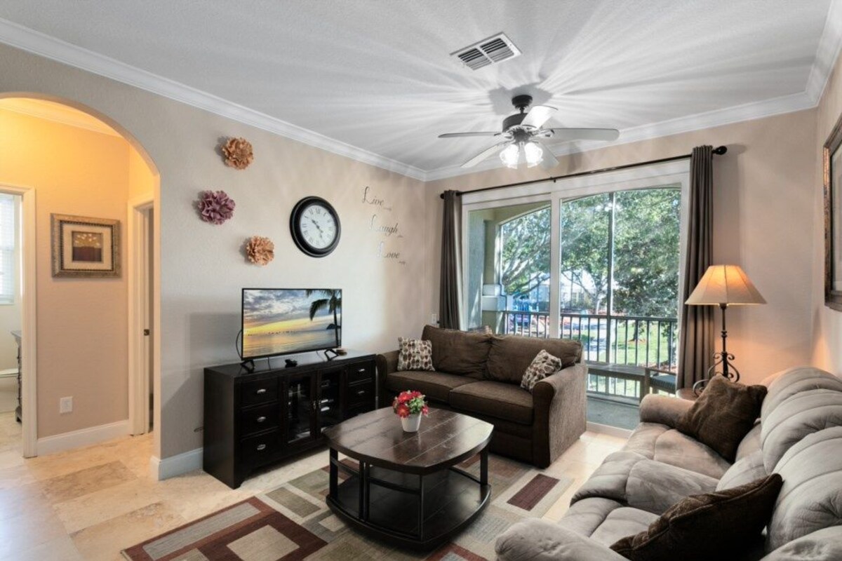 A living room with a sofa, coffee table, TV, and a ceiling fan.